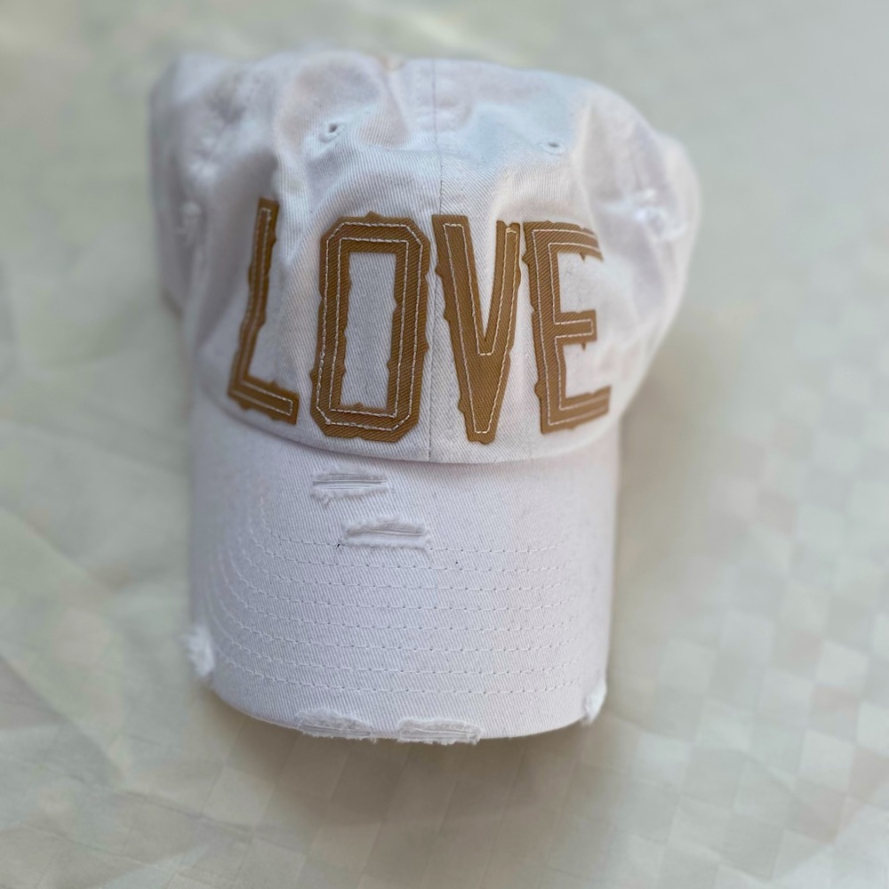 White baseball cap. Hat that says LOVE in the front. Lightly torn texture